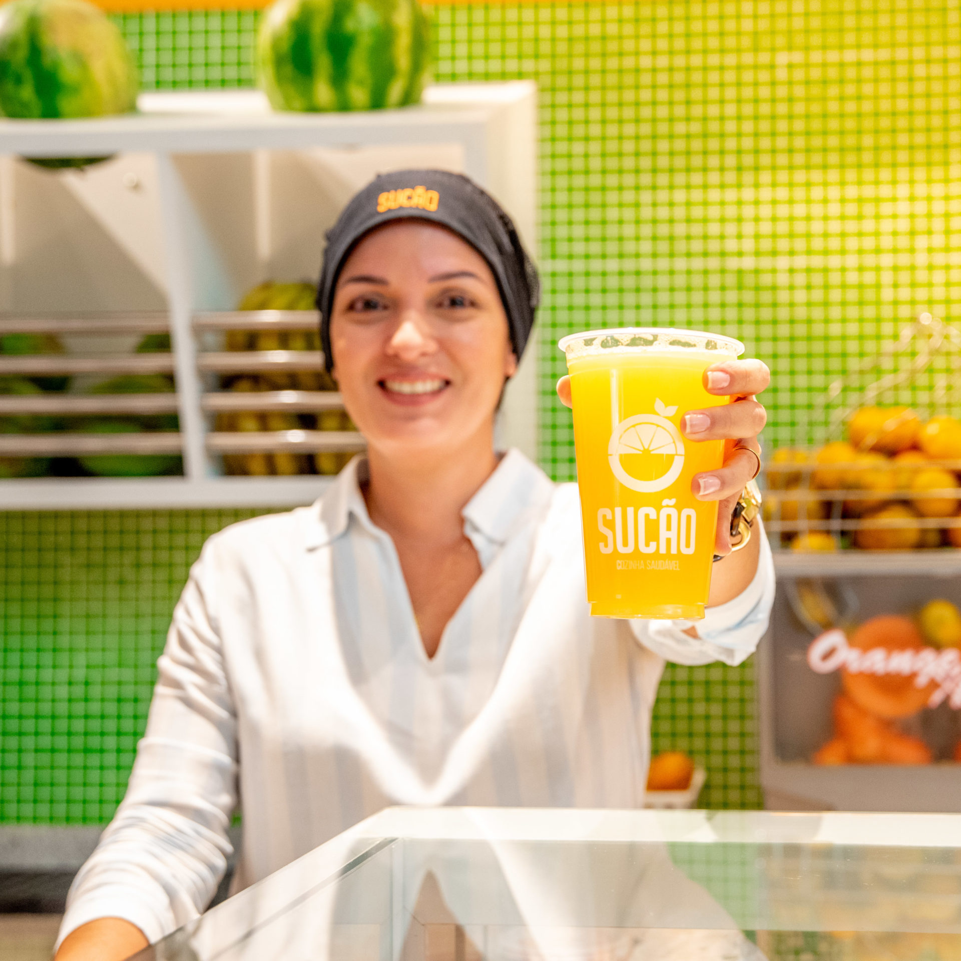 mulher de branco segurando suco de laranja em restaurante de shopping