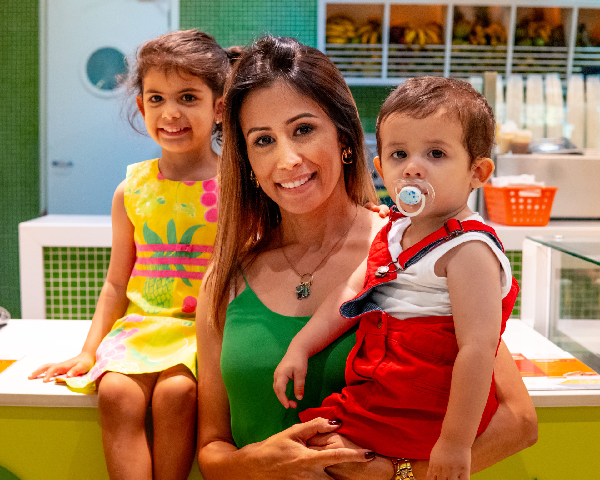 Mulher com duas crianças em frente a uma loja de sucos